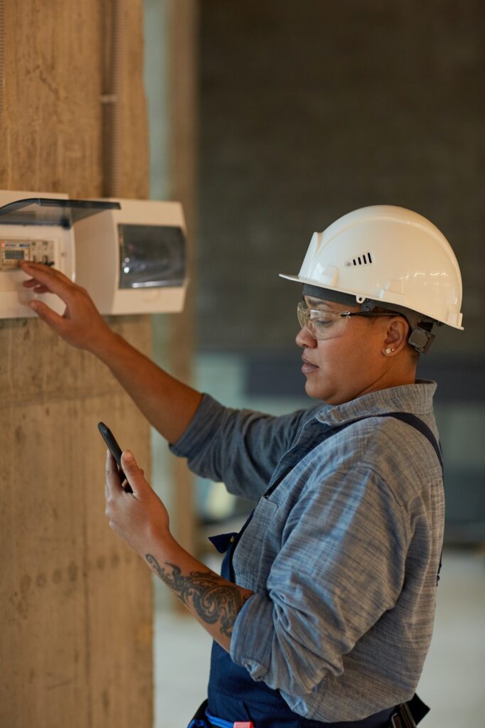 Female Electrician Inspecting Switchboard